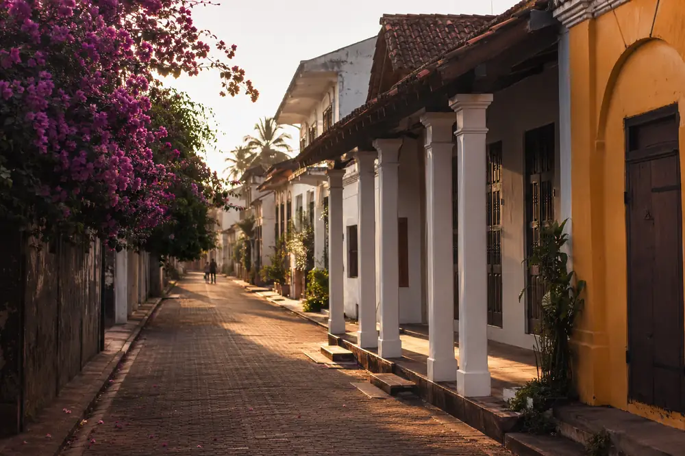 Golden hour lane inside Galle Fort with colonnaded colonial facades and bougainvillea