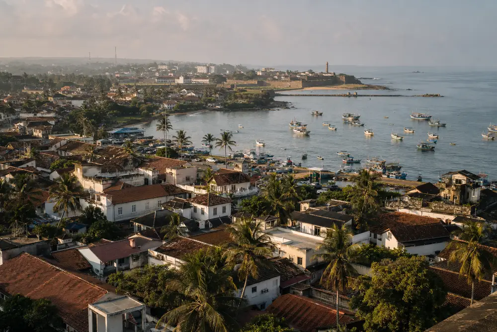 View over Galle town rooftops and the fishing harbor with the Fort and lighthouse in the distance