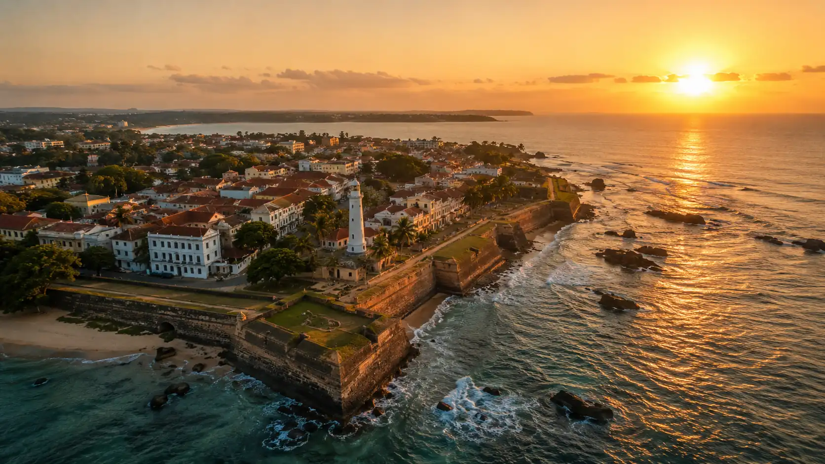 Aerial view of Galle Fort at sunset with the lighthouse, the ramparts and the sun setting over the Indian Ocean