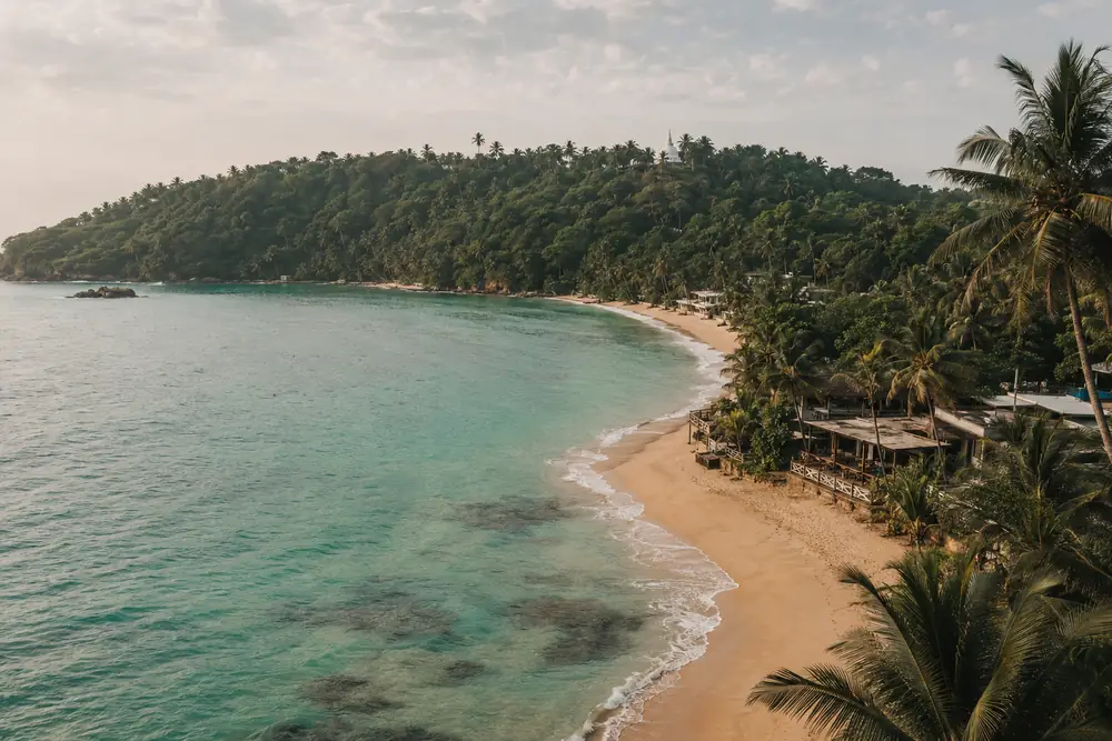 Aerial view of Unawatuna's horseshoe bay with the Peace Pagoda on the jungle headland